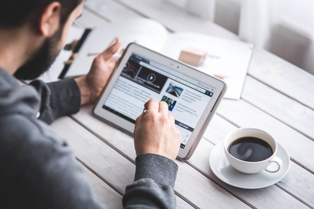 pessoa lendo uma notícia no tablet, simbolizando o que é notícia e a estrutura da notícia